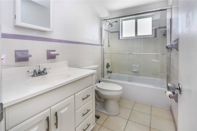 full bathroom with bath / shower combo with glass door, vanity, tile walls, tile patterned flooring, and toilet