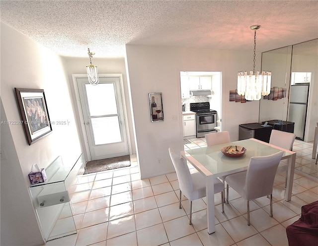 tiled dining area featuring a textured ceiling and a chandelier