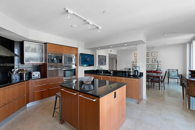 kitchen featuring a kitchen bar, rail lighting, sink, a kitchen island, and stainless steel microwave