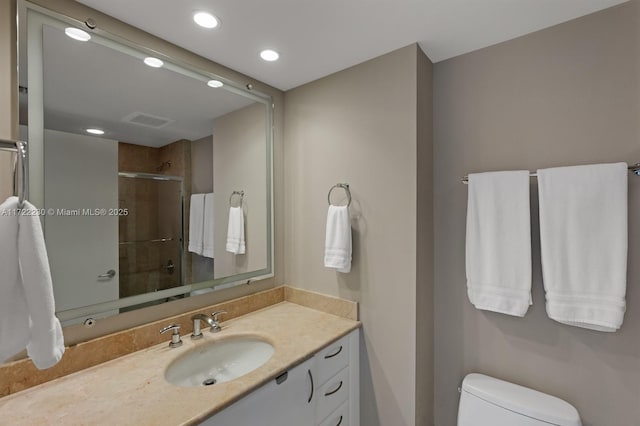 bathroom with vanity, toilet, and a shower with door