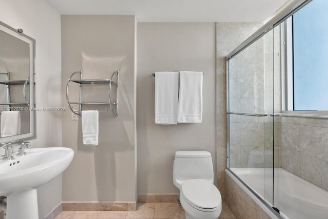 full bathroom featuring tile patterned floors, sink, bath / shower combo with glass door, and toilet