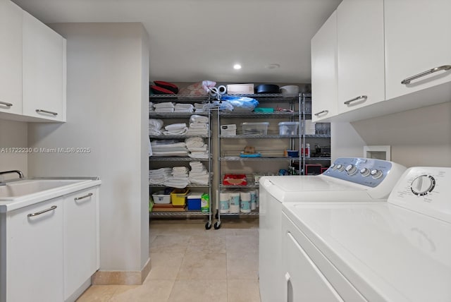 laundry area featuring washing machine and clothes dryer, sink, light tile patterned floors, and cabinets