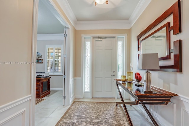 foyer featuring wainscoting, light tile patterned flooring, crown molding, and a decorative wall