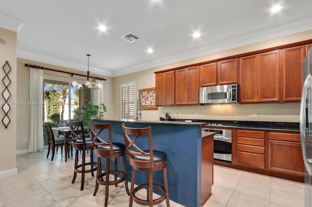 kitchen featuring hanging light fixtures, an inviting chandelier, crown molding, a center island with sink, and appliances with stainless steel finishes