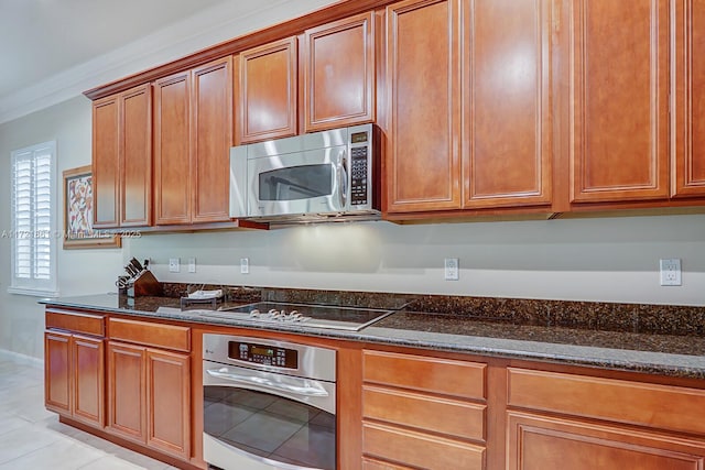 kitchen featuring appliances with stainless steel finishes, ornamental molding, and dark stone countertops