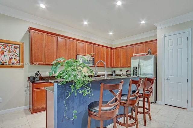 kitchen with a kitchen bar, a kitchen island with sink, light tile patterned flooring, and stainless steel appliances