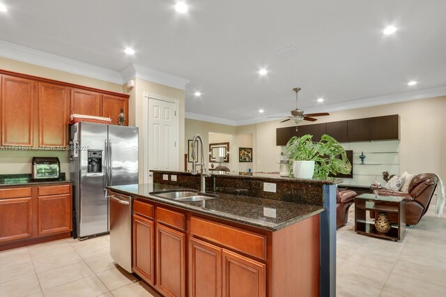 kitchen with a center island with sink, sink, ceiling fan, dark stone countertops, and stainless steel appliances