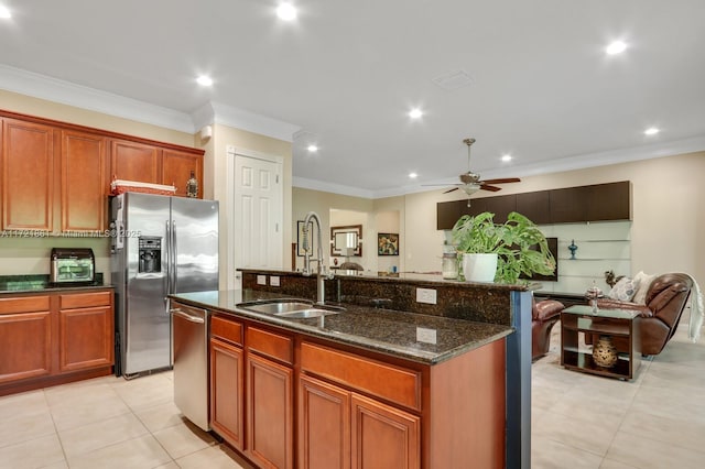 kitchen featuring a center island with sink, stainless steel appliances, open floor plan, a sink, and dark stone counters