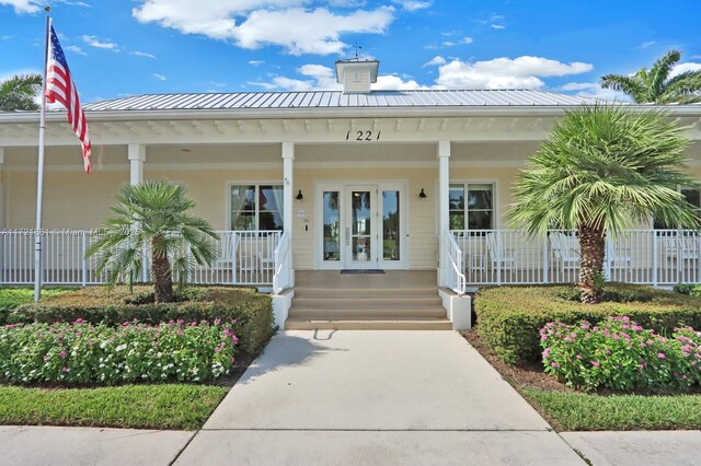 view of exterior entry featuring covered porch, metal roof, and a standing seam roof