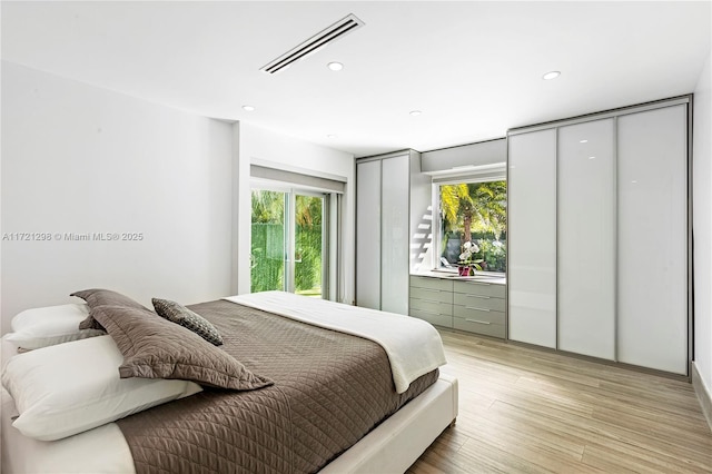 bedroom with light wood-type flooring and multiple windows