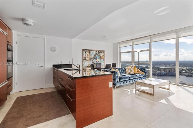 kitchen featuring kitchen peninsula, a water view, floor to ceiling windows, and light tile patterned flooring