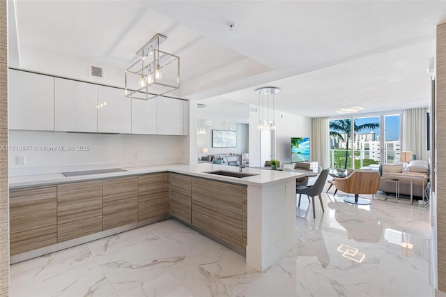 kitchen with white cabinets, pendant lighting, kitchen peninsula, and sink