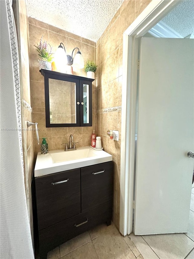 bathroom featuring tile patterned flooring, vanity, tile walls, and a textured ceiling