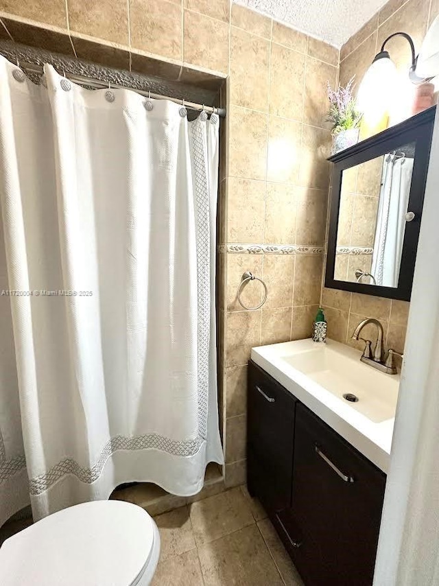 bathroom featuring vanity, backsplash, toilet, tile walls, and a textured ceiling