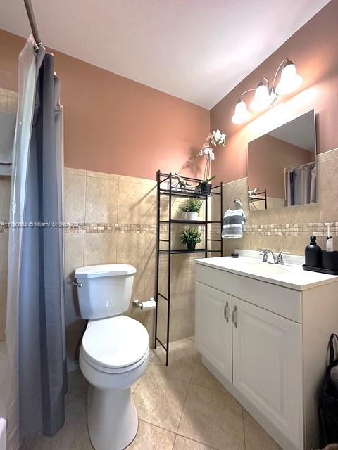 bathroom featuring tile patterned flooring, vanity, toilet, and tile walls