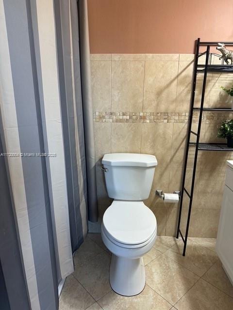 bathroom with tile patterned flooring, vanity, toilet, and tile walls