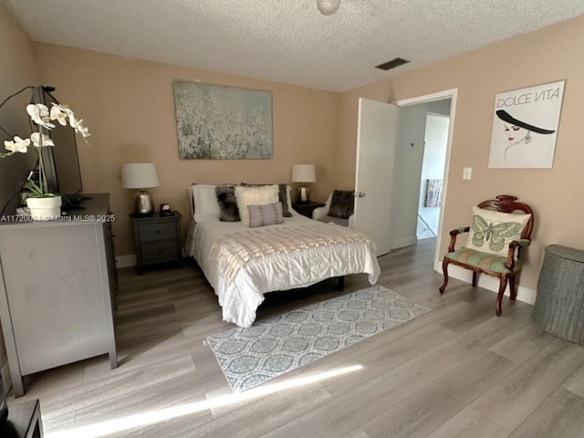 bedroom featuring light wood-type flooring and a textured ceiling