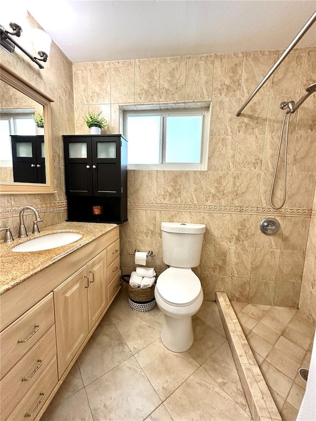 bathroom featuring tile patterned floors, vanity, tiled shower, tile walls, and toilet