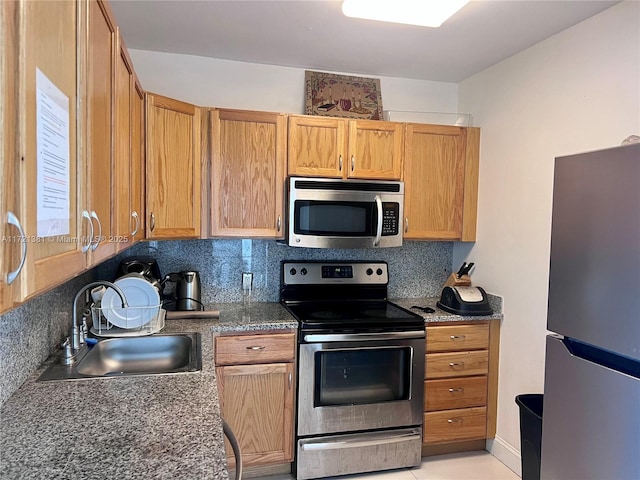 kitchen featuring backsplash, sink, light tile patterned floors, and appliances with stainless steel finishes