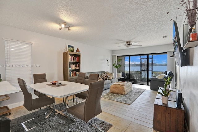 tiled dining area with ceiling fan and a textured ceiling