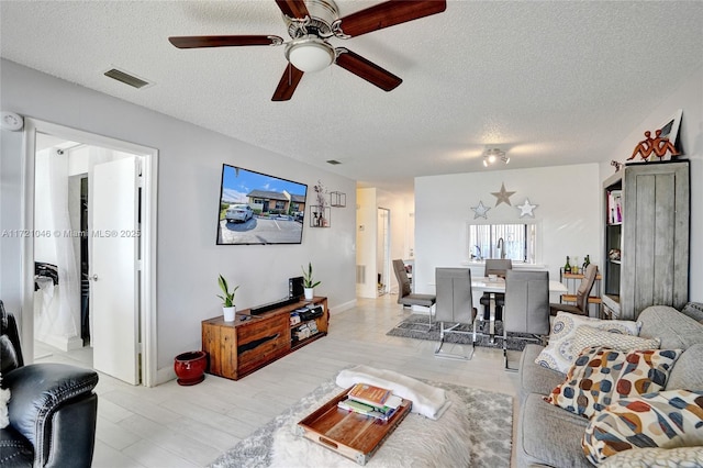 living room featuring ceiling fan and a textured ceiling