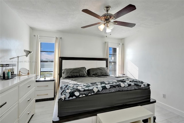 bedroom featuring ceiling fan, light hardwood / wood-style floors, and a textured ceiling