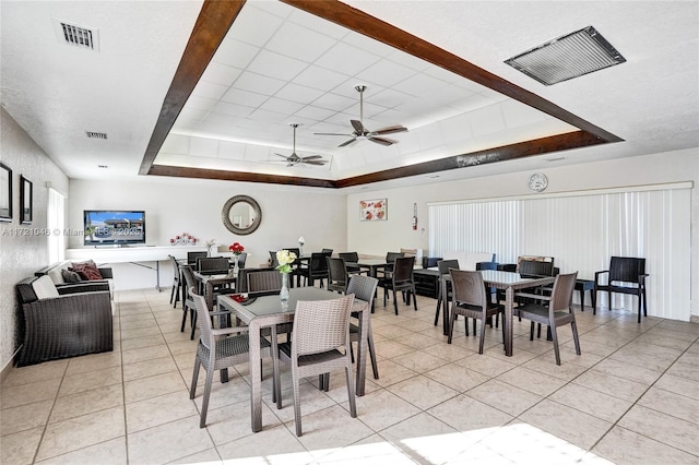 tiled dining area with a raised ceiling and ceiling fan