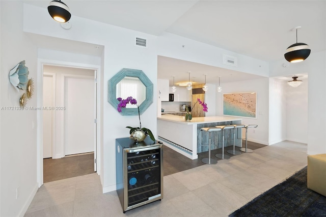 kitchen with pendant lighting, white cabinets, a breakfast bar area, and wine cooler