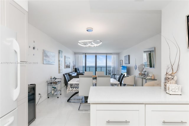 kitchen featuring white cabinets, decorative light fixtures, white refrigerator, and a wall of windows