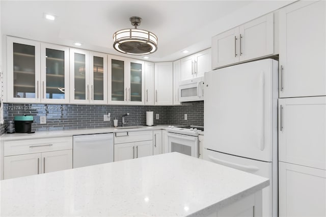 kitchen with white appliances, backsplash, white cabinets, sink, and light stone counters