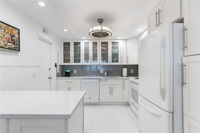 kitchen featuring white appliances, backsplash, white cabinets, sink, and light tile patterned flooring