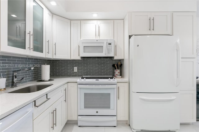 kitchen with white cabinetry, sink, tasteful backsplash, light stone counters, and white appliances