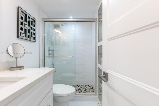 bathroom with tile patterned floors, vanity, toilet, and a shower with shower door