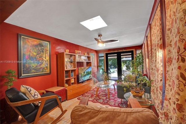 sitting room with ceiling fan, french doors, light tile patterned floors, and a skylight