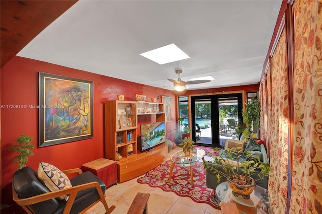 sitting room featuring a skylight, ceiling fan, french doors, and light tile patterned floors