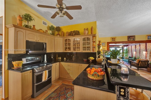 kitchen featuring appliances with stainless steel finishes, light brown cabinetry, lofted ceiling, and sink