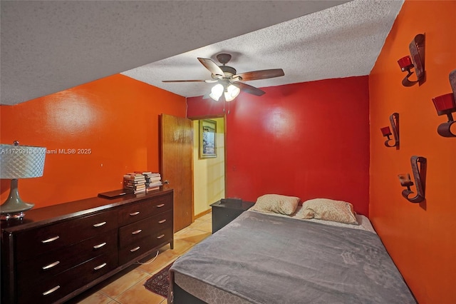 bedroom with ceiling fan, light tile patterned floors, and a textured ceiling