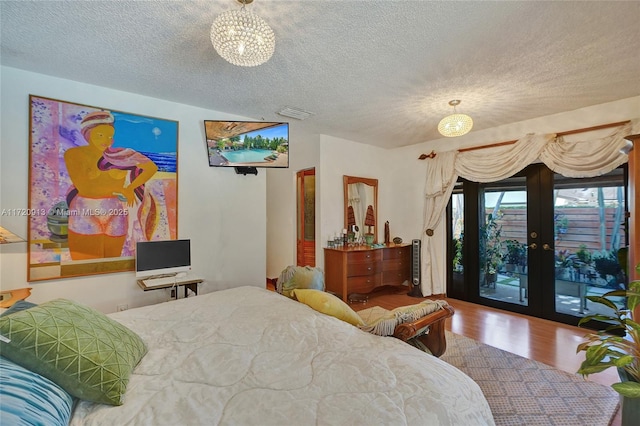 bedroom with hardwood / wood-style floors, access to outside, french doors, a textured ceiling, and a chandelier