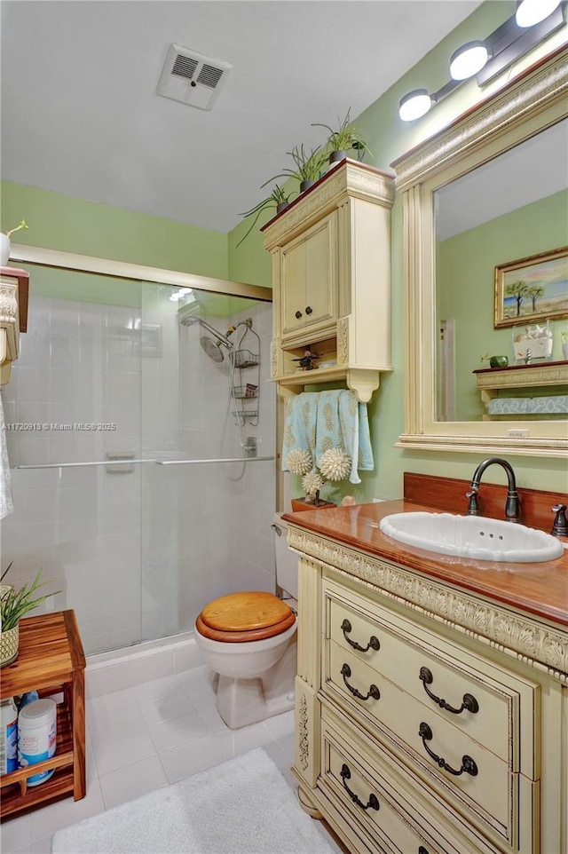 bathroom featuring tile patterned flooring, toilet, an enclosed shower, and vanity