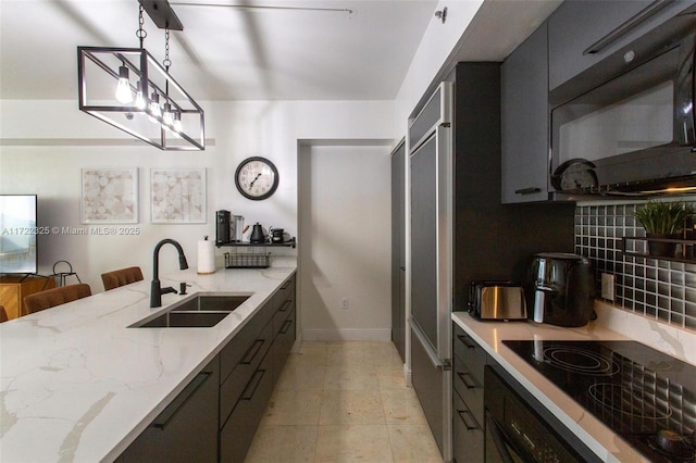 kitchen with sink, light stone counters, pendant lighting, a kitchen bar, and black electric cooktop