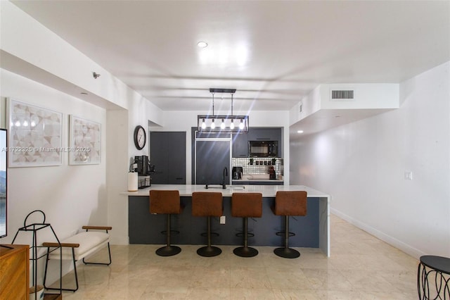 kitchen featuring a breakfast bar area, kitchen peninsula, sink, and hanging light fixtures