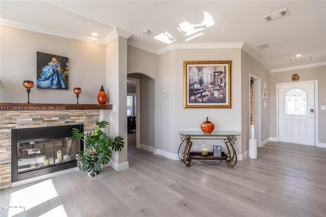 entryway with crown molding, a fireplace, and light hardwood / wood-style floors