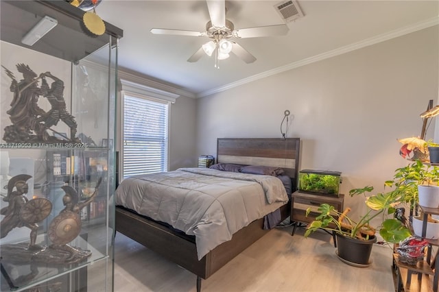 bedroom with hardwood / wood-style floors, ceiling fan, and crown molding