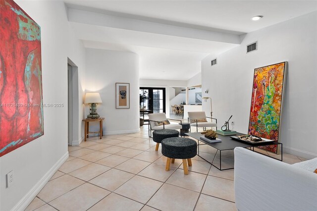 living room featuring lofted ceiling with beams, light tile patterned floors, and french doors