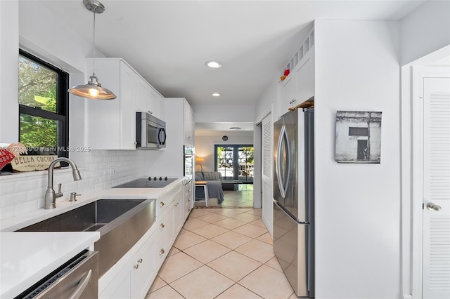 kitchen with sink, white cabinetry, hanging light fixtures, appliances with stainless steel finishes, and backsplash