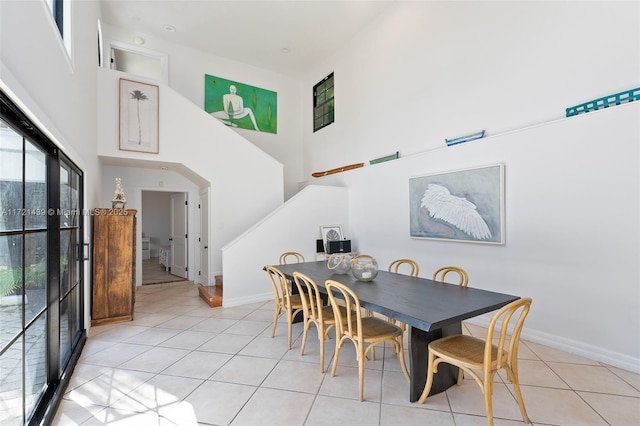 dining space featuring a high ceiling and light tile patterned flooring