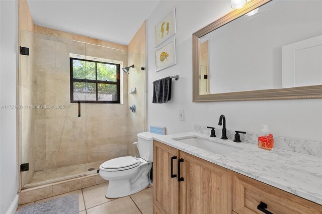 bathroom featuring walk in shower, vanity, toilet, and tile patterned flooring