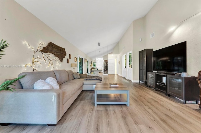 living room featuring high vaulted ceiling and light hardwood / wood-style flooring