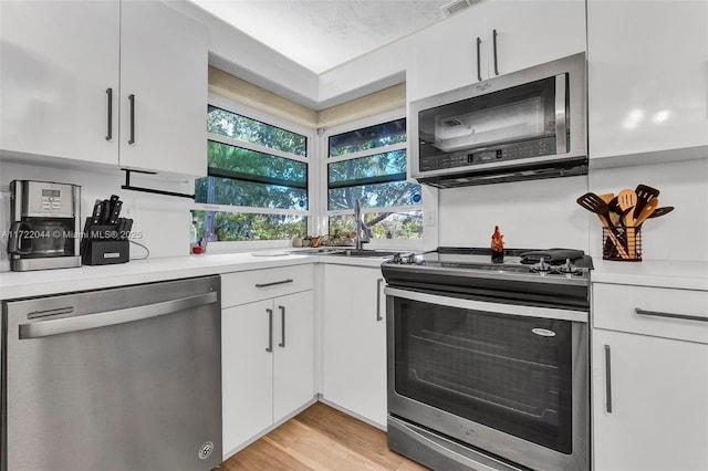 kitchen with white cabinets, plenty of natural light, sink, and stainless steel appliances