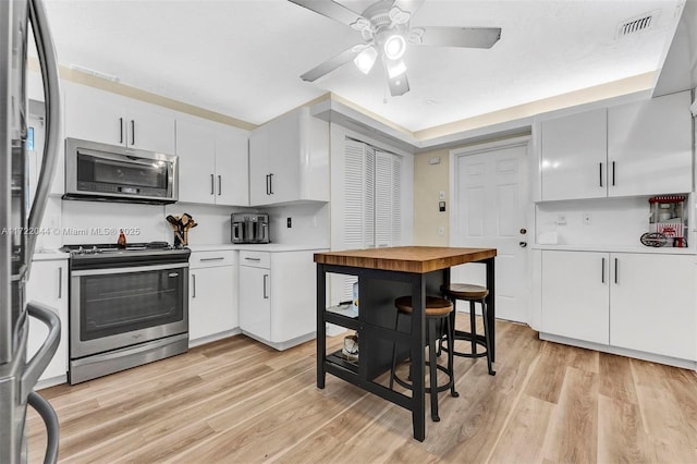 kitchen with ceiling fan, white cabinets, light wood-type flooring, and appliances with stainless steel finishes